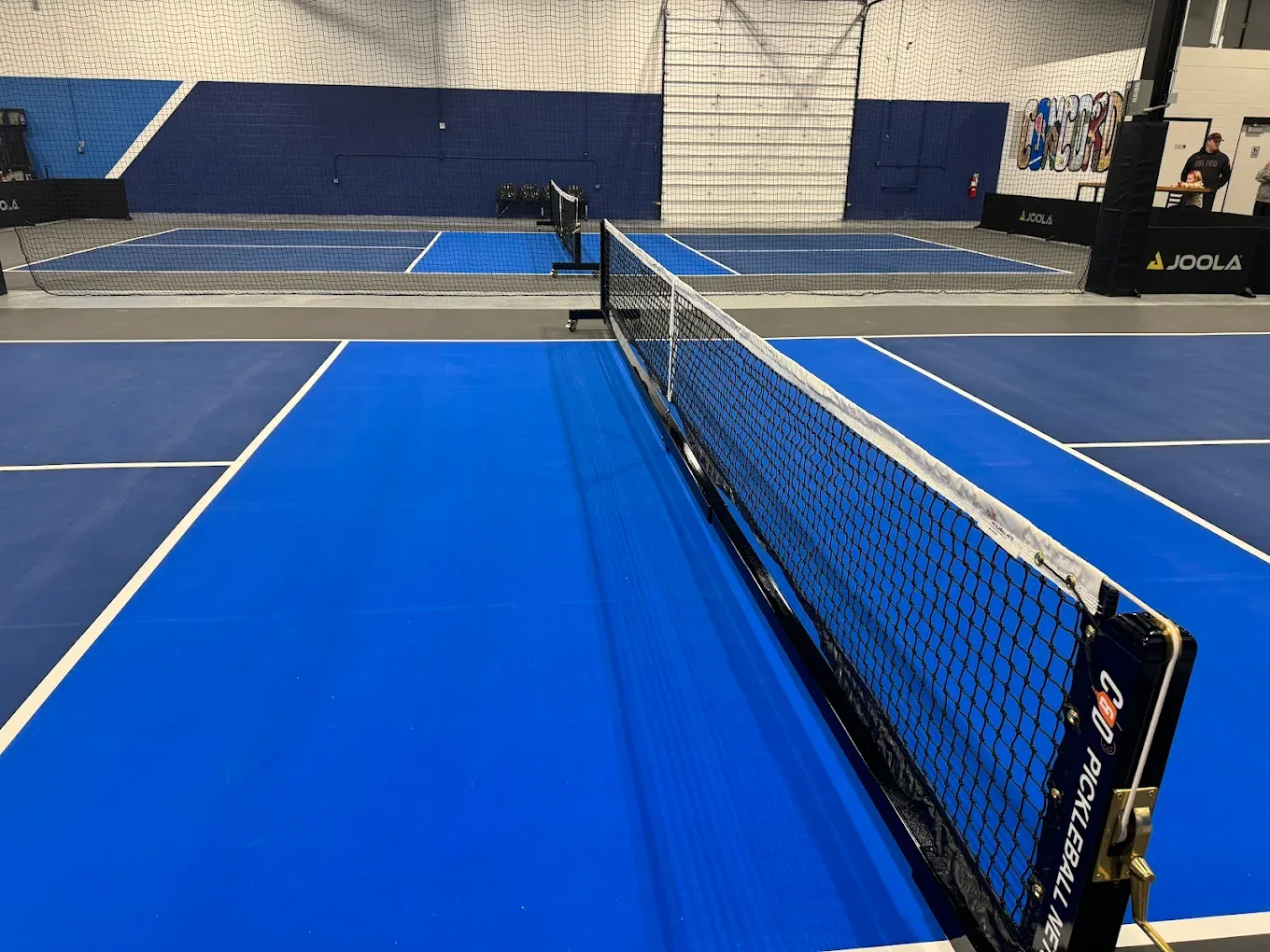 Two indoor pickleball courts with JOOLA nets